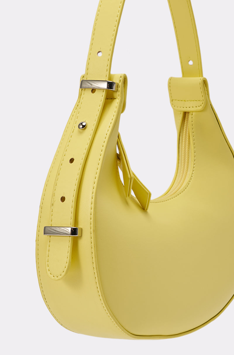 A close-up of the GET WITH THE TREND PU PURSE, a yellow crescent shoulder bag featuring an adjustable strap, silver-tone hardware, and detailed stitching, crafted from PU material, set against a plain white background. 4