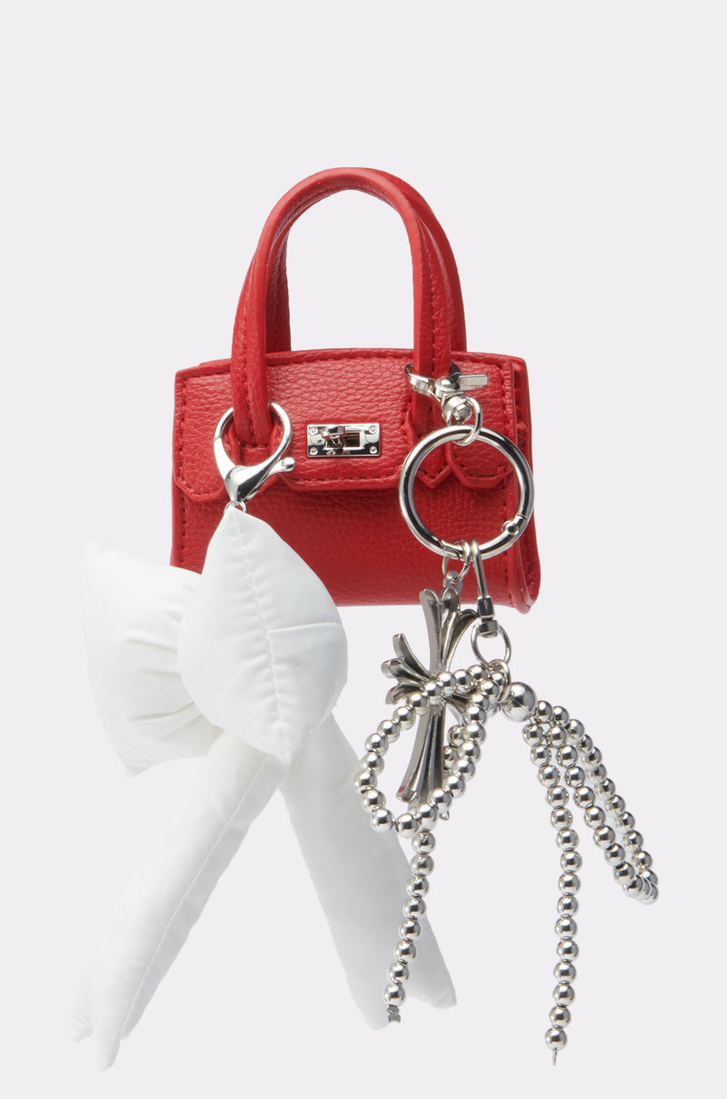 The SO CUTE SO MINI PURSE is a small red handbag keychain featuring a white fabric bow, metallic keyring, and silver beaded ball chains, shown against a plain light background. 0