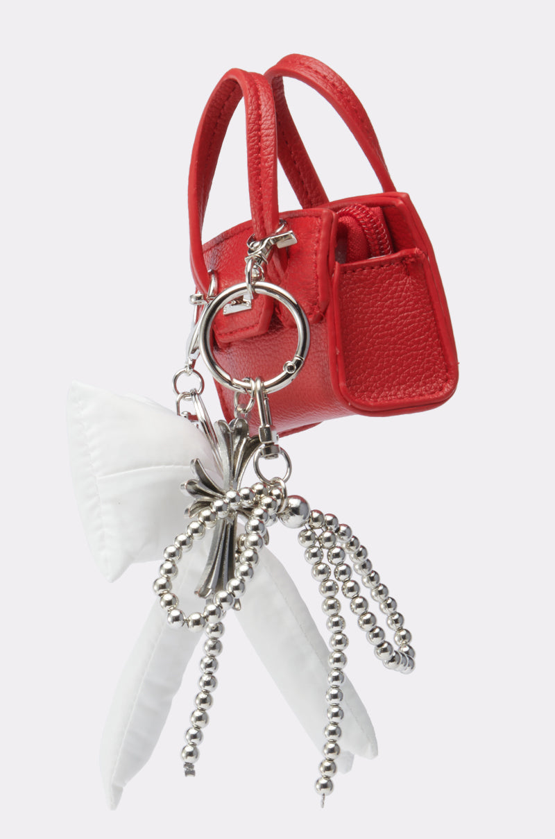 The SO CUTE SO MINI PURSE is a small red purse-shaped keychain with a silver keyring, metallic chains, and white fabric accents, displayed against a plain white background. 2