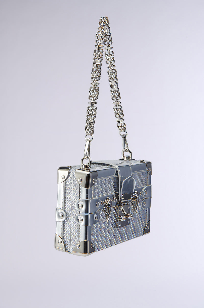 The LOU BLING TRUNK BAG is a small silver bag with metal corners, chain strap, and a textured crystal-studded surface covered in silver rhinestones, shown against a plain light background.