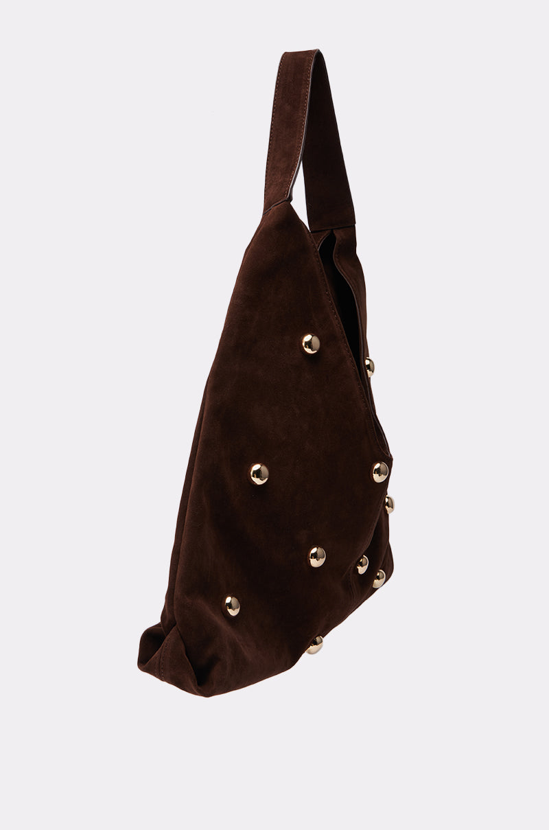 The TAYLOR SUEDE BALL TOTE is a dark brown faux suede shoulder bag with a single strap and gold round studs, shown against a plain light background.