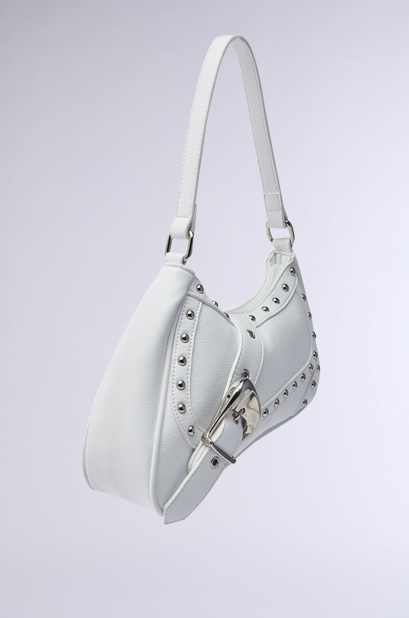 The BELLA PURSE is a white faux leather handbag with silver studs, an oversized buckle, and a single shoulder strap, shown against a plain light background. 3