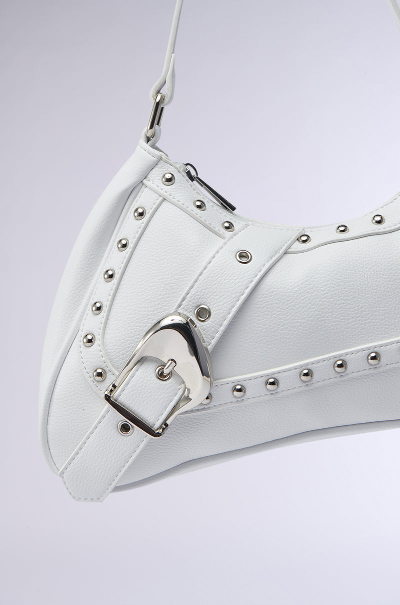 Close-up of the BELLA PURSE, a white faux leather handbag featuring silver studs and an oversized buckle. Its modern, structured design brings a chic touch to any outfit. Shown on a light gray background. 4