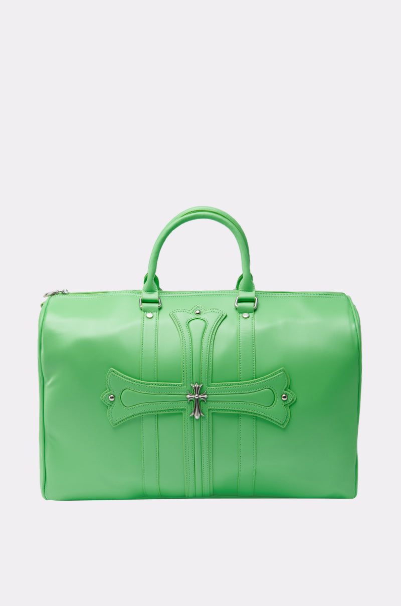The SHE DIFFERENT DUFFEL BAG is a lime green faux leather duffel with two handles, a silver zipper, decorative stitched cross, silver hardware, and modern metal accents on the front.