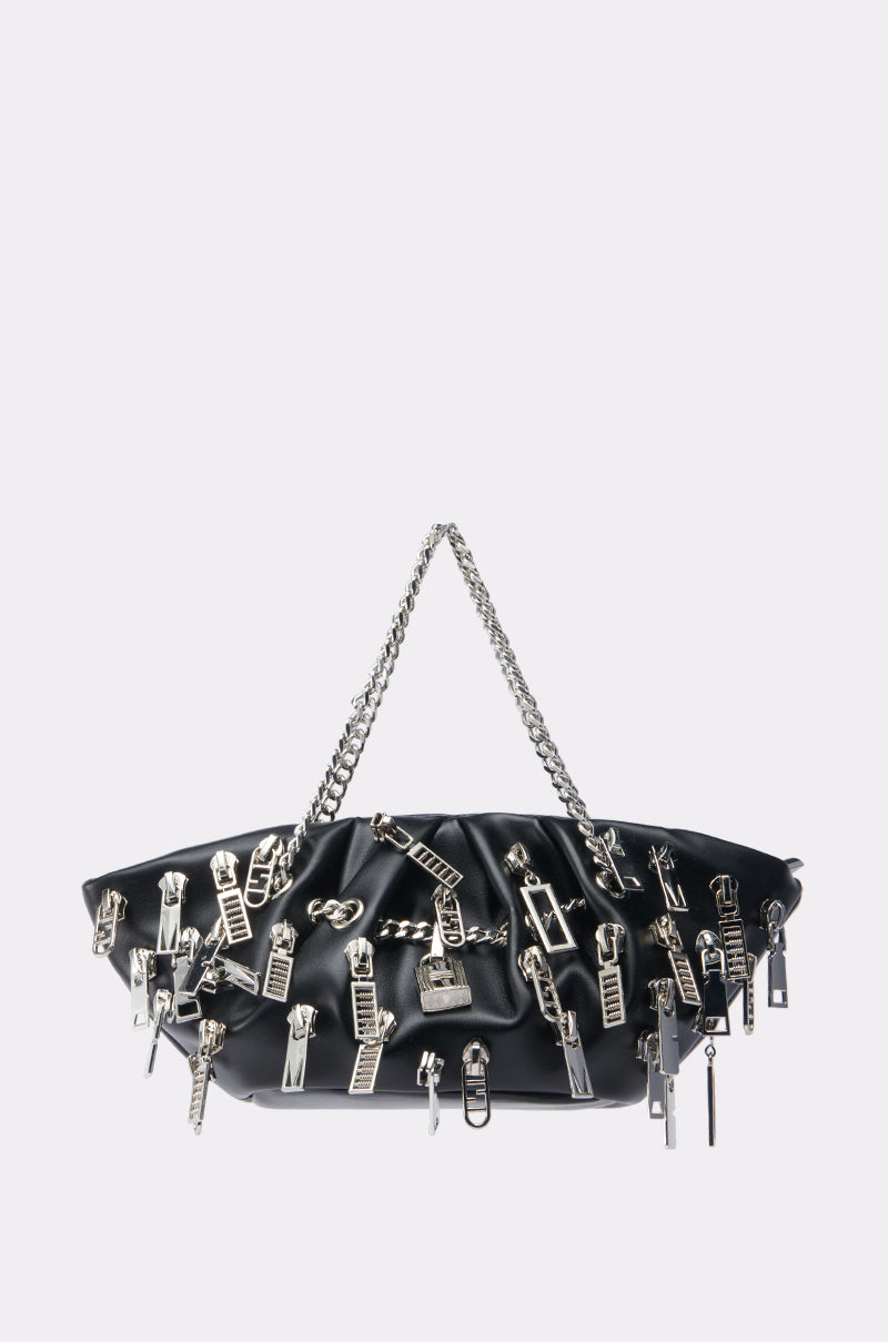 The ZIP IT CHARM PURSE is a black faux leather bag with a silver chain strap and bold street-style charm, featuring scattered silver zipper pulls and teeth, set against a plain light background.