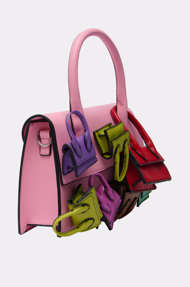The IN MY BAGS PURSE is a baby pink faux leather bag with a top handle, colorful mini handbags in purple, green, red, and brown on the front and sides, plus a detachable shoulder strap for versatile styling. 2