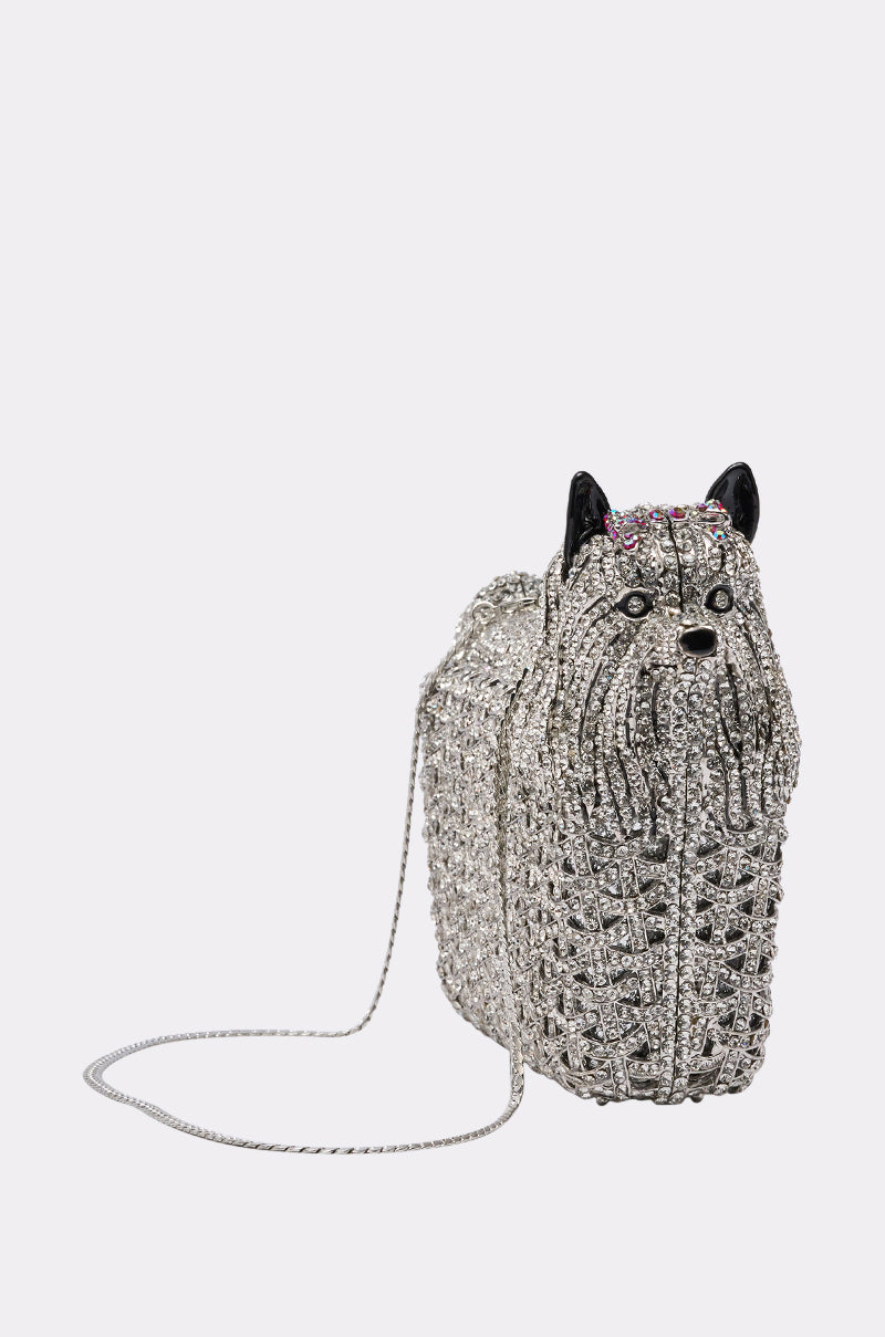 The CHARMAINE BLING PURSE is a sparkly, dog-shaped purse covered in rhinestones with black ears, a chain strap, and detailed features—perfect for adding playful glamour to any outfit.