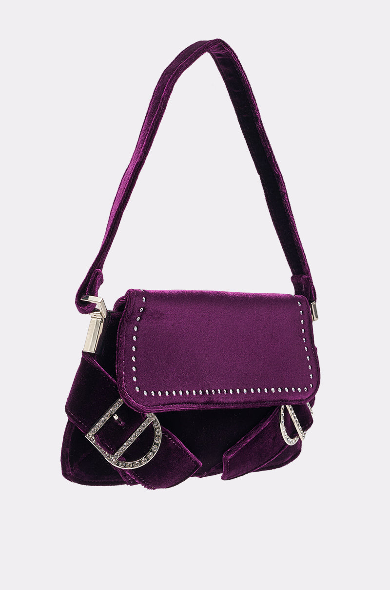 The LEILA VELVET PURSE is a small, deep purple bag featuring a thick strap, silver studs on the flap, and two decorative silver "D" accents on the front. 2