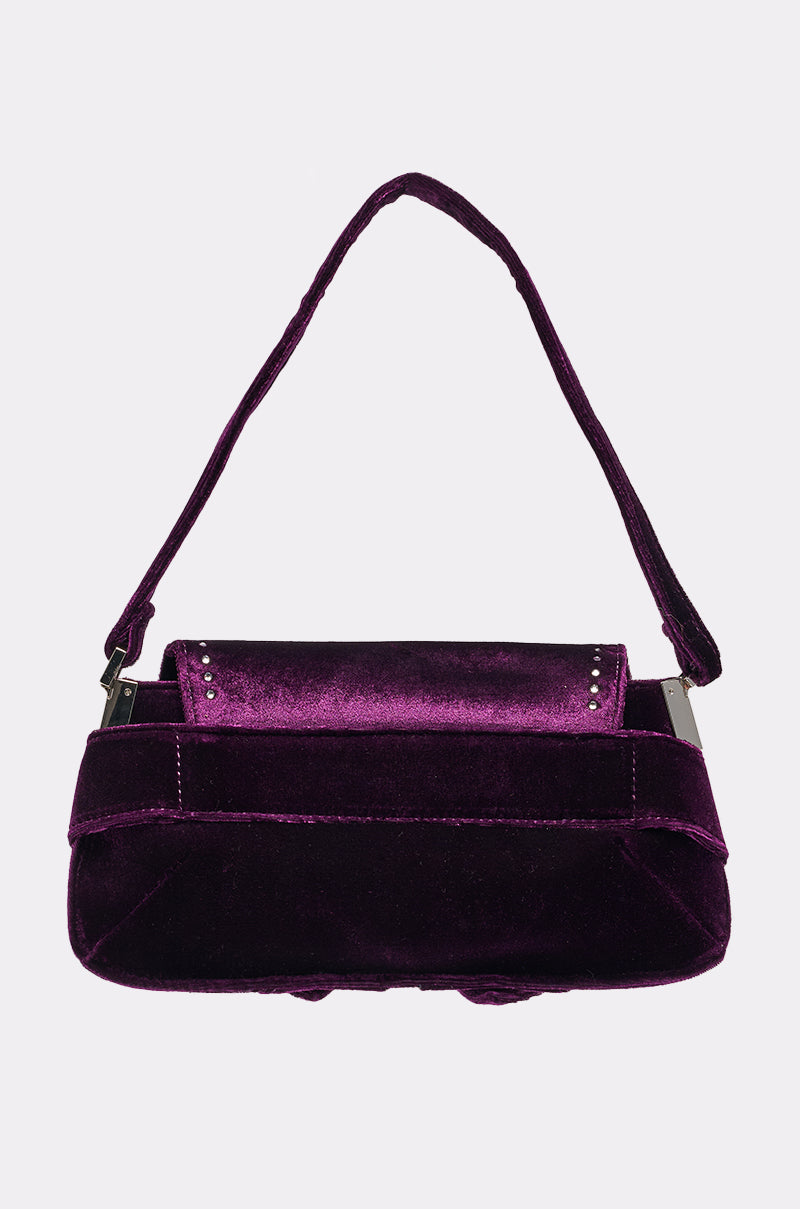 The LEILA VELVET PURSE, a small rectangular purple bag with silver studs, a short matching handle, and structured design, is shown against a light grey background—an ideal velvet baguette for stylish evening outings. 3