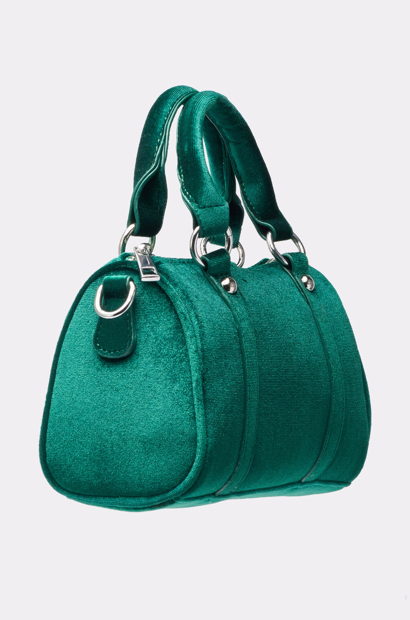 The JESSI VELVET PURSE, a small structured green handbag with a soft velvet finish, silver hardware, and two matching handles, is showcased against a plain light background. 2