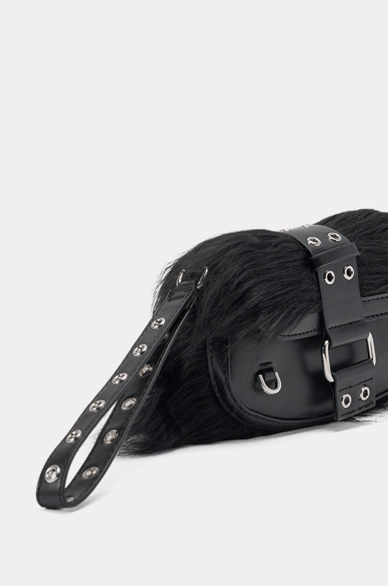 A close-up of the ON THE TOWN WRISTLET, a black faux leather handbag with faux fur texture, featuring silver eyelets, a metal buckle, and an eyelet-adorned handle—perfect for a night out—displayed on a light gray background. 4
