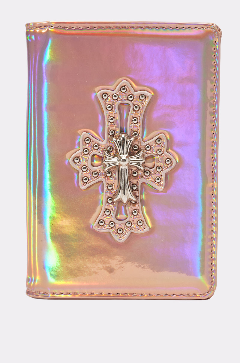 The FEELIN ROSIE PASSPORT COVER is an iridescent pink faux leather passport holder with a metallic cross accent and intricate studded details on the front.