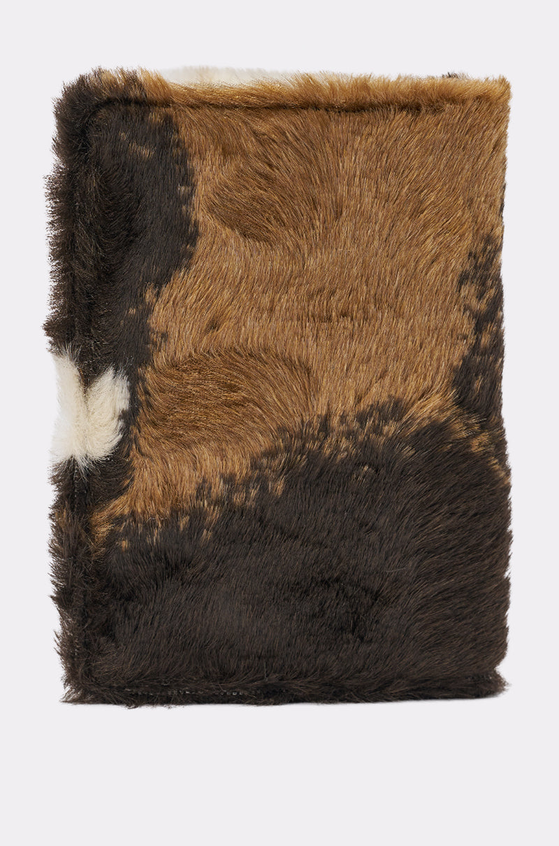 A brown and white faux fur passport cover inspired by cow print—perfect for keeping your travel essentials cozy and stylish on your next trip. 3