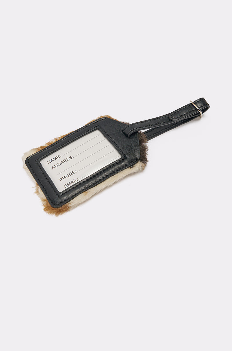 The HIGH STANDARDS FAUX FUR LUGGAGE TAG is a black faux leather tag with fur-trimmed edges, a buckle strap, and an info card for name, address, phone, and email. Shown against a white background. 2