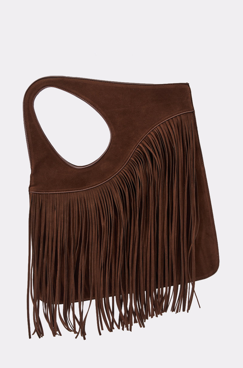 The FRINGED OUT SHOULDER PURSE is a brown boho-chic faux suede bag with an asymmetrical handle and long front fringe, shown against a plain, light background. 0