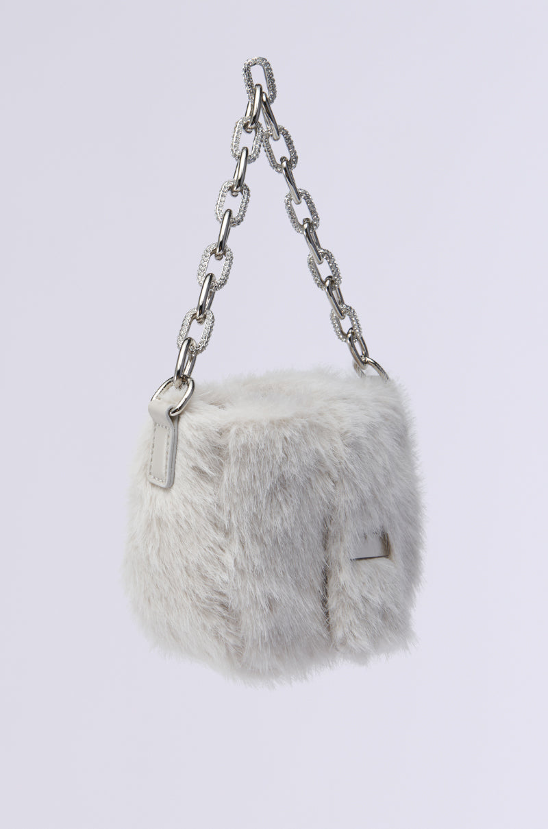 The JACQUES FAUX FUR MINI PURSE is a small, cube-shaped accessory adorned in soft white faux fur, complemented by a shiny silver chain strap. Despite its minimalist design and compact size, it boasts a surprisingly spacious interior. A tag is attached to the side against an uncluttered white background. 2