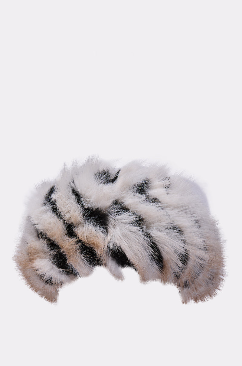 Keep warm in style with the PORTIA FAUX FUR HEADBAND, featuring a fluffy striped mix of white, black, and light brown, shown against a plain light background. 2