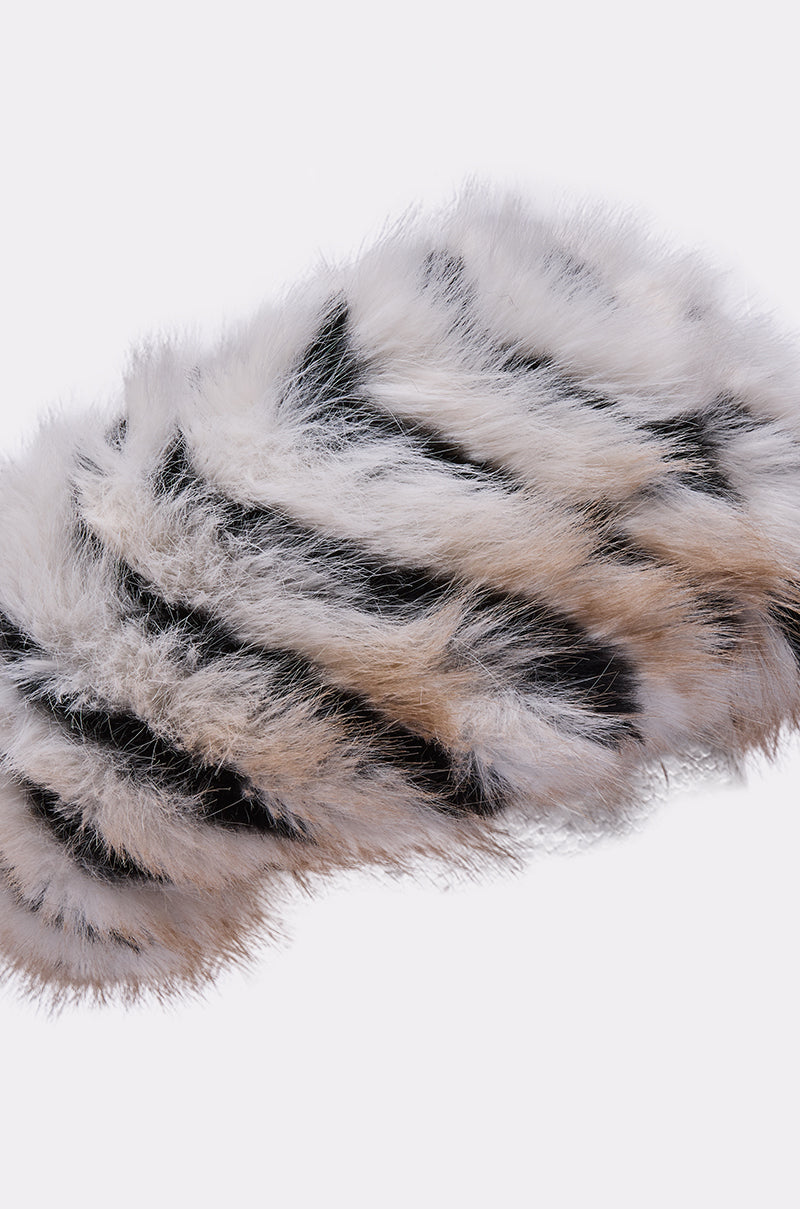 The PORTIA FAUX FUR HEADBAND is a fluffy, striped accessory in white, black, and tan with a satin lining, shown on a plain white background—perfect for adding style and warmth in cold weather. 4