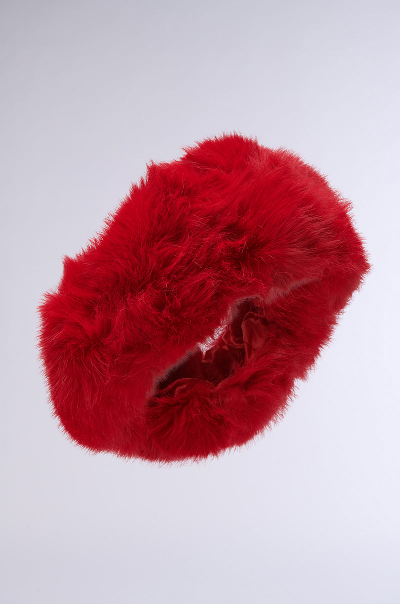 The LOOK AT ME NOW FAUX FUR HEADBAND, with its fluffy texture and vibrant red hue, appears to float effortlessly against a light gray background, highlighting its stretchy over-the-ear fit in mid-air. 3
