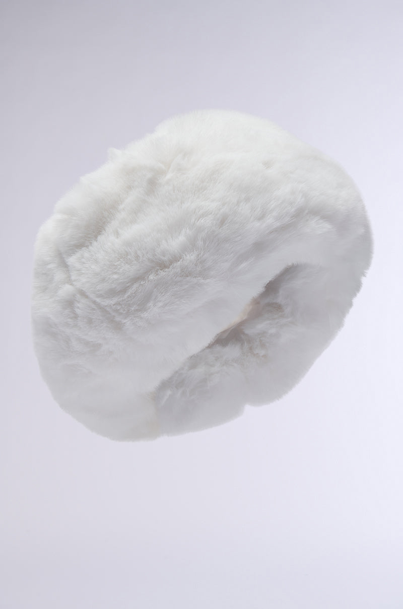 A LUXE JENNY FAUX FUR HEADBAND, featuring a fluffy, white texture, is set against a light gray background. This cozy winter accessory is round with a soft, plush feel akin to a circular loop.