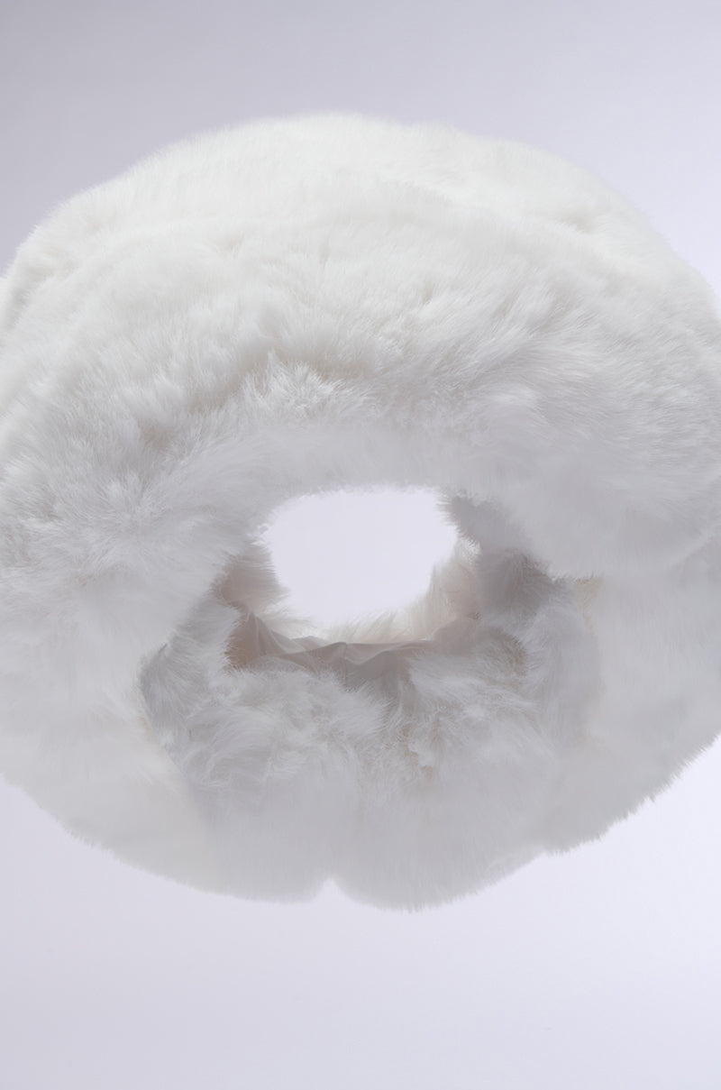 A pillow shaped like a donut, showcasing a fluffy and plush white exterior, reminiscent of the LUXE JENNY FAUX FUR HEADBAND. Set against a simple light background, it promises both comfort and style for resting or as an elegant decorative piece.
