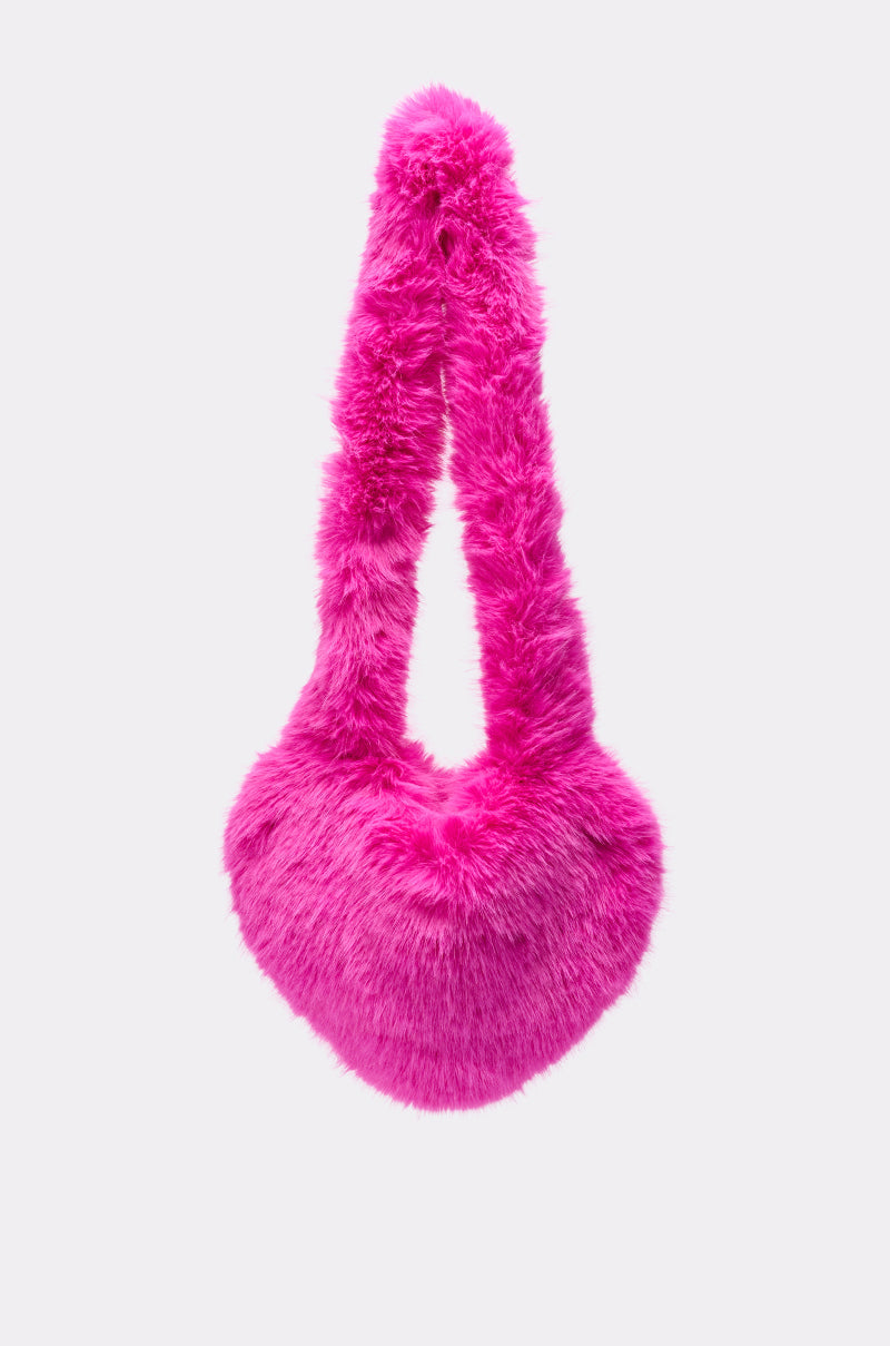 The LANA FAUX FUR HEART BAG IN PINK features a bright pink, heart-shaped design with a matching fluffy handle, shown against a plain light background. 0