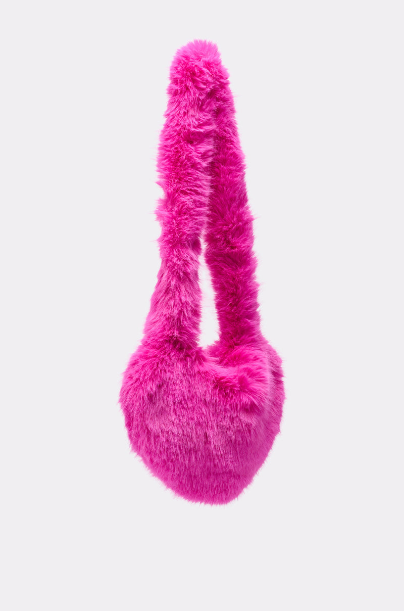 The LANA FAUX FUR HEART BAG IN PINK, featuring a bright pink fluffy faux fur heart-shaped body and a thick, soft handle, is displayed against a plain light background. 2