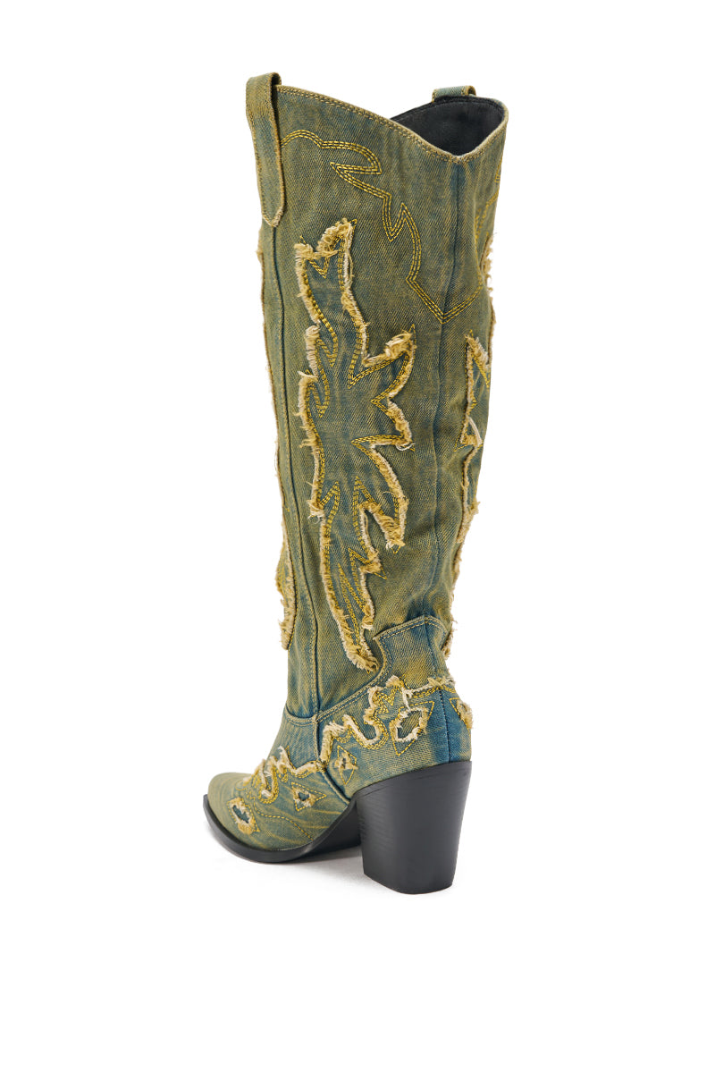 The AZALEA WANG HEINRICH DENIM WESTERN LOW HEEL BOOT is a tall, greenish denim boot with frayed yellow leaf-pattern stitching, a pointed toe, and chunky black heel, shown against a white background.