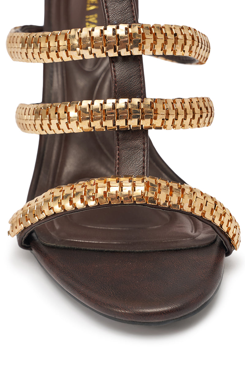 A close-up of the AZALEA WANG HERSILIE BROWN GLADIATOR STILETTO shows ankle-high stilettos in dark brown leather with three gold chain-link straps across the foot. 8