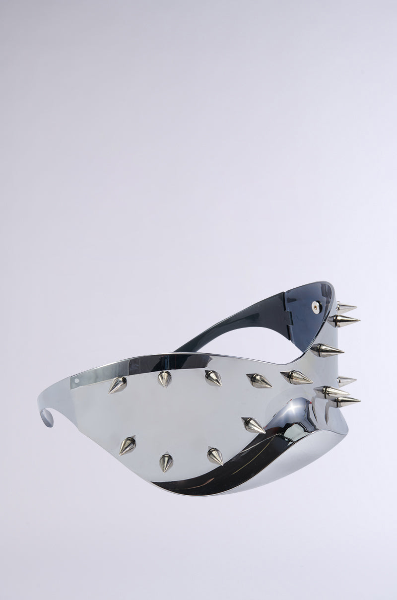 Introducing the BACK UP STUDDED SUNGLASSES: a futuristic pair of oversized shield sunglasses featuring a high-gloss finish and adorned with multiple silver spikes on the frames and temples. The lenses and frame are seamlessly integrated into a sleek, curvilinear design that exudes a modern, edgy appearance.