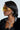 A person with sleek black hair sports the BOUJEE BISH SUNGLASSES, showcasing oversized rectangular frames and yellow-tinted lenses. Their look is enhanced by silver accessories such as a bold chain necklace with a cross pendant and large earrings, paired effortlessly with a textured black jacket.