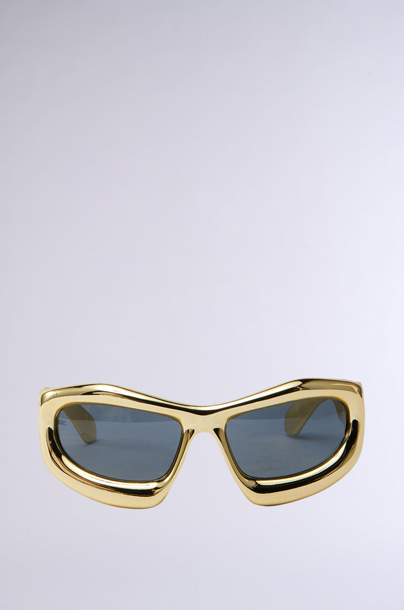 The IM SO TRENDY SUNGLASSES have gold frames and tinted lenses, displayed on a light gray background. With an angular, modern design, these stylish sunglasses are the ultimate fashion accessory.