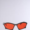 SEEING RED SUNGLASSES with a sleek design featuring vibrant red-tinted lenses and black frames, set against a plain light gray background.