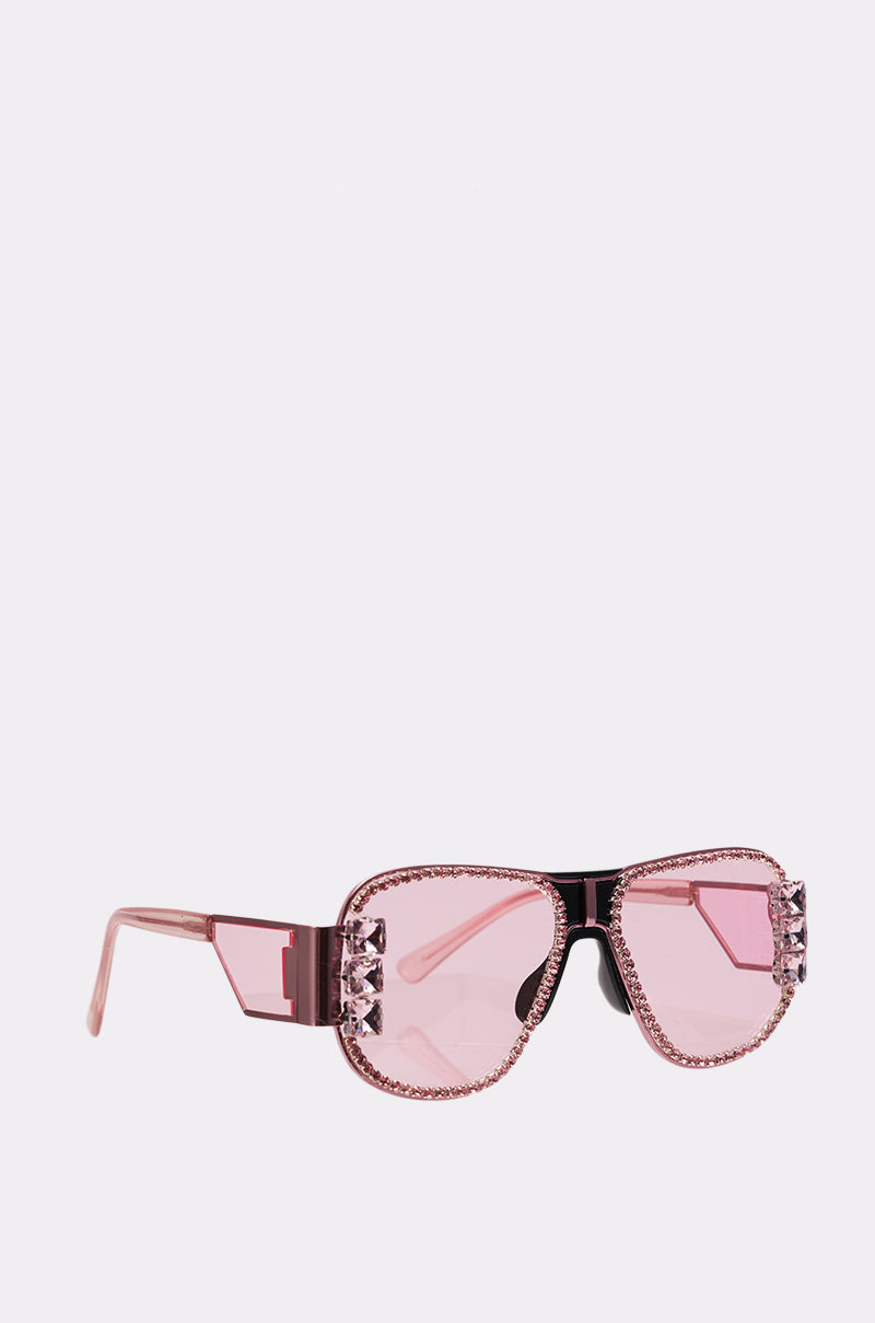 PRETTY IN PINK SUNGLASSES feature pink-tinted lenses, sparkling rhinestones on the frames and corners, and wide pink arms, shown against a plain light background.