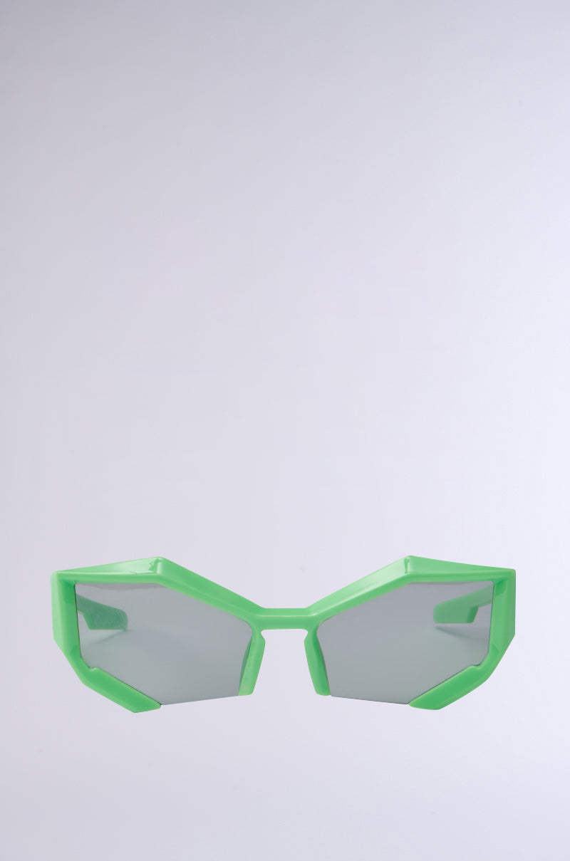The TO THE FUTURE SUNGLASSES feature bold, geometric cat eye silhouettes with striking bright green frames against a plain, light background.