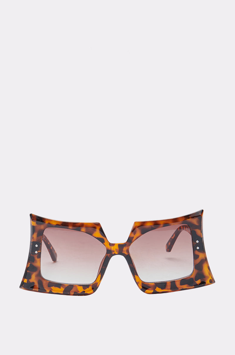 The SHELLY SUNGLASSES feature a tortoiseshell pattern, oversized square frames with flared edges, and brown gradient lenses for a retro chic look, shown against a plain light background. 0