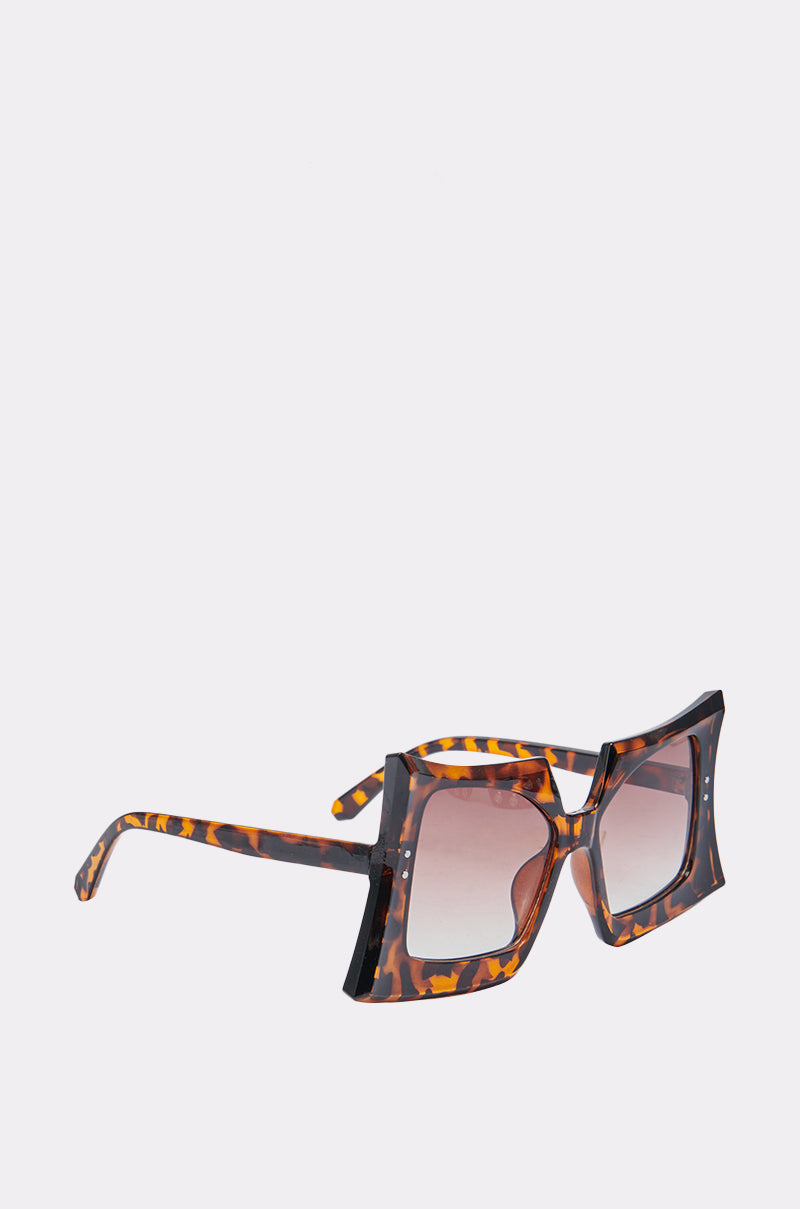 The SHELLY SUNGLASSES feature an oversized brown tortoiseshell frame with gradient brown lenses, offering retro-chic style and shown against a plain light background.