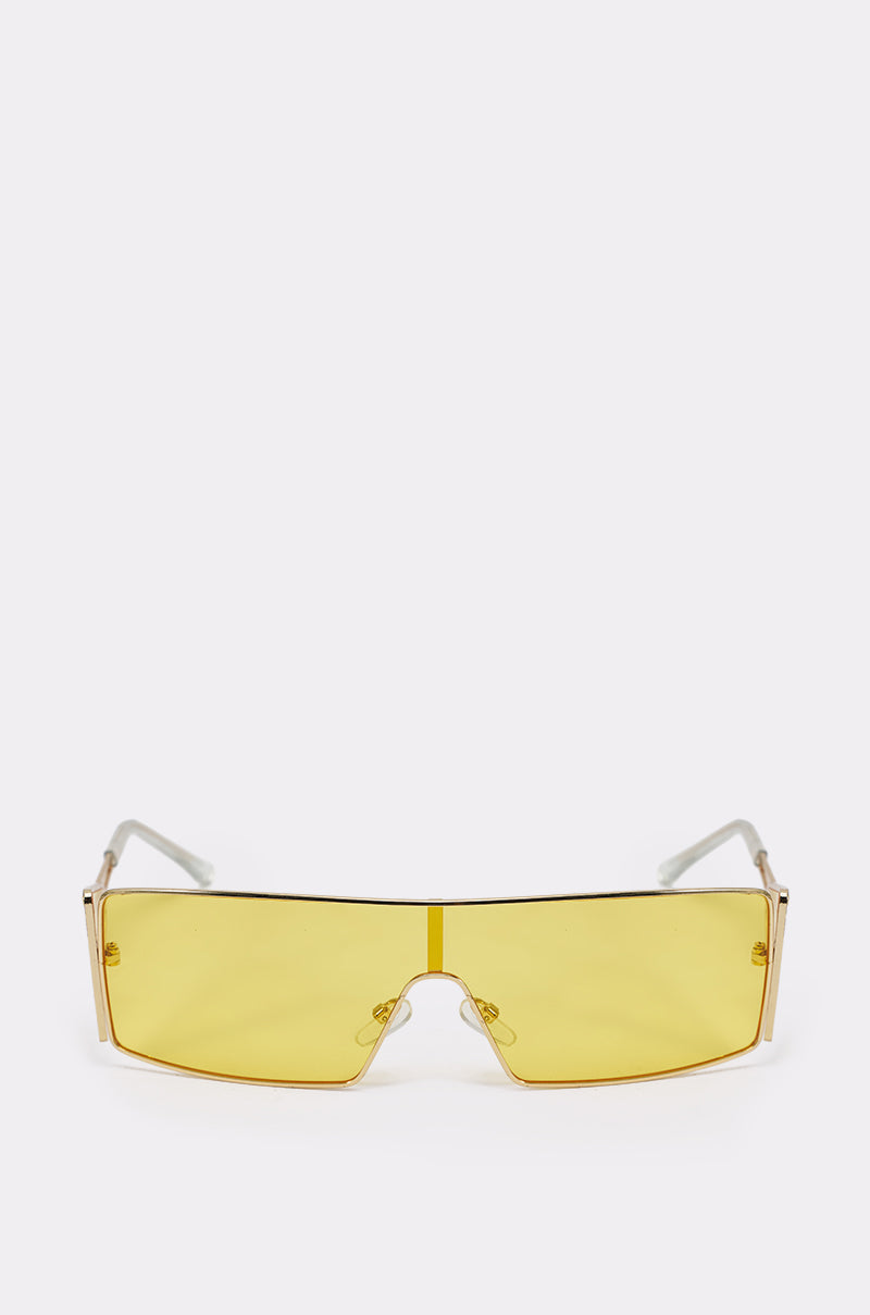 The LEMON TWIST SUNGLASSES are yellow shield festival shades with a single wide rectangular lens and thin clear arms, shown against a plain white background. 1