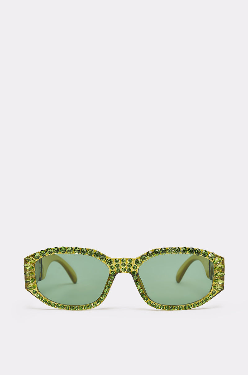 The CATCH MY VIBE SUNGLASSES feature green crystal rectangular lenses and a bold chunky frame, adorned with shimmering gemstones along the top and sides, creating standout statement eyewear against a plain white background. 0
