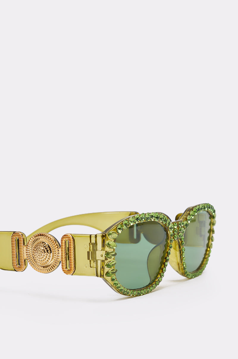 CATCH MY VIBE SUNGLASSES: Yellow-green statement shades with green-tinted lenses, rhinestone-embellished frames, and a gold Medusa medallion on the temples, displayed against a plain white background. 4