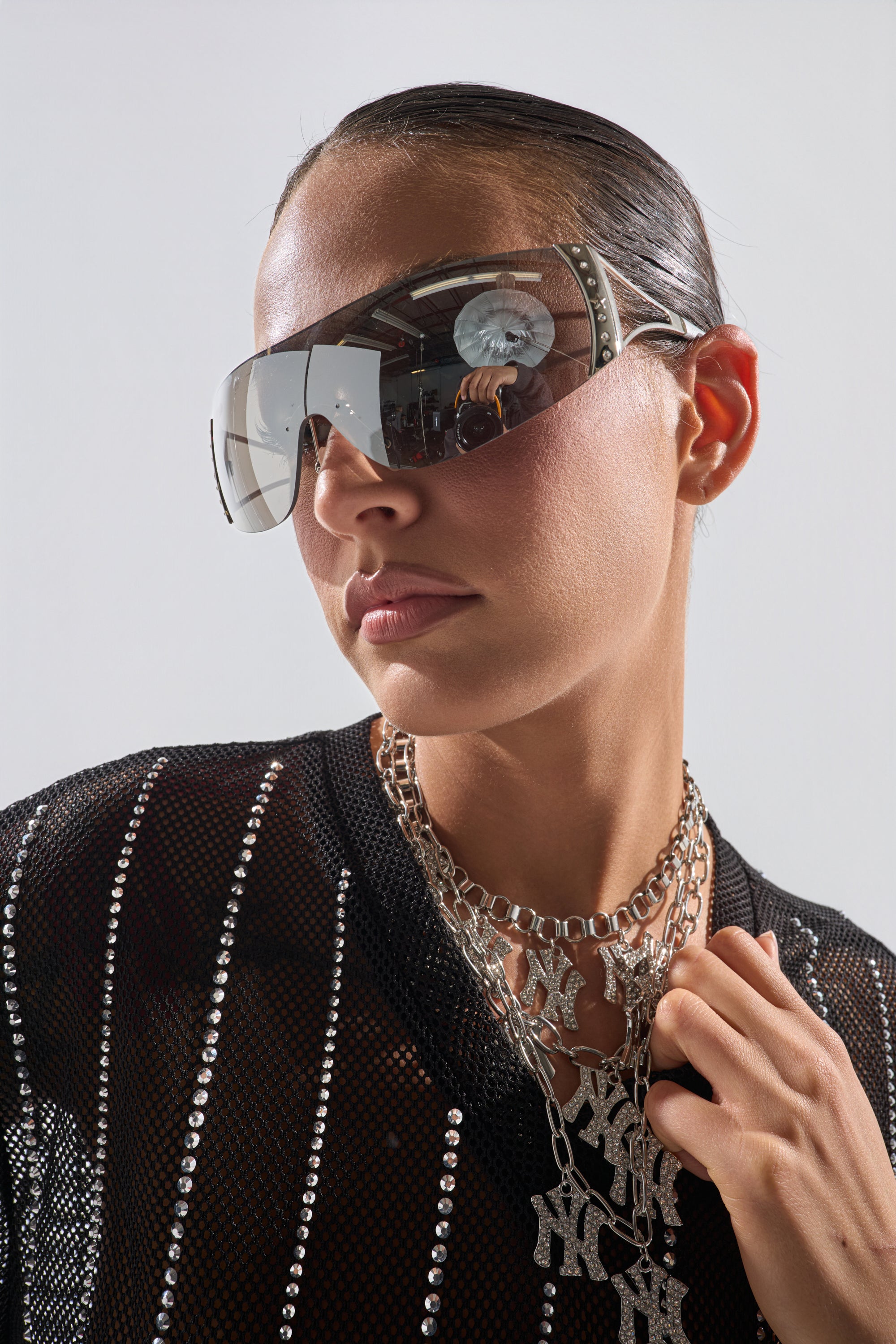 A woman wearing EVERY DAY SUNGLASSES, a black shirt, and a silver necklace. 1