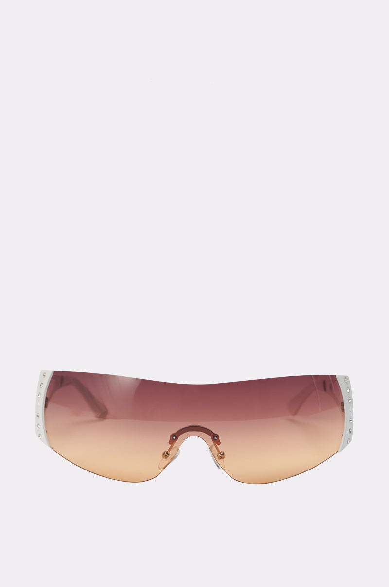 The NEUTRALEYES SUNGLASSES are oversized Y2K shield sunglasses with a pink-to-brown gradient lens and white accents on the outer edges of the rimless frame. 0