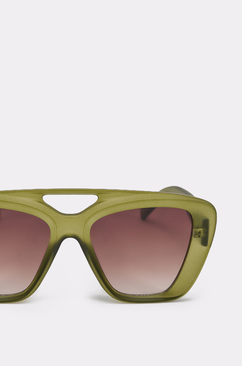 Close-up of the MAL SUNGLASSES in olive green, featuring brown gradient lenses and a unique cut-out above the nose bridge, set against a light gray background. 4