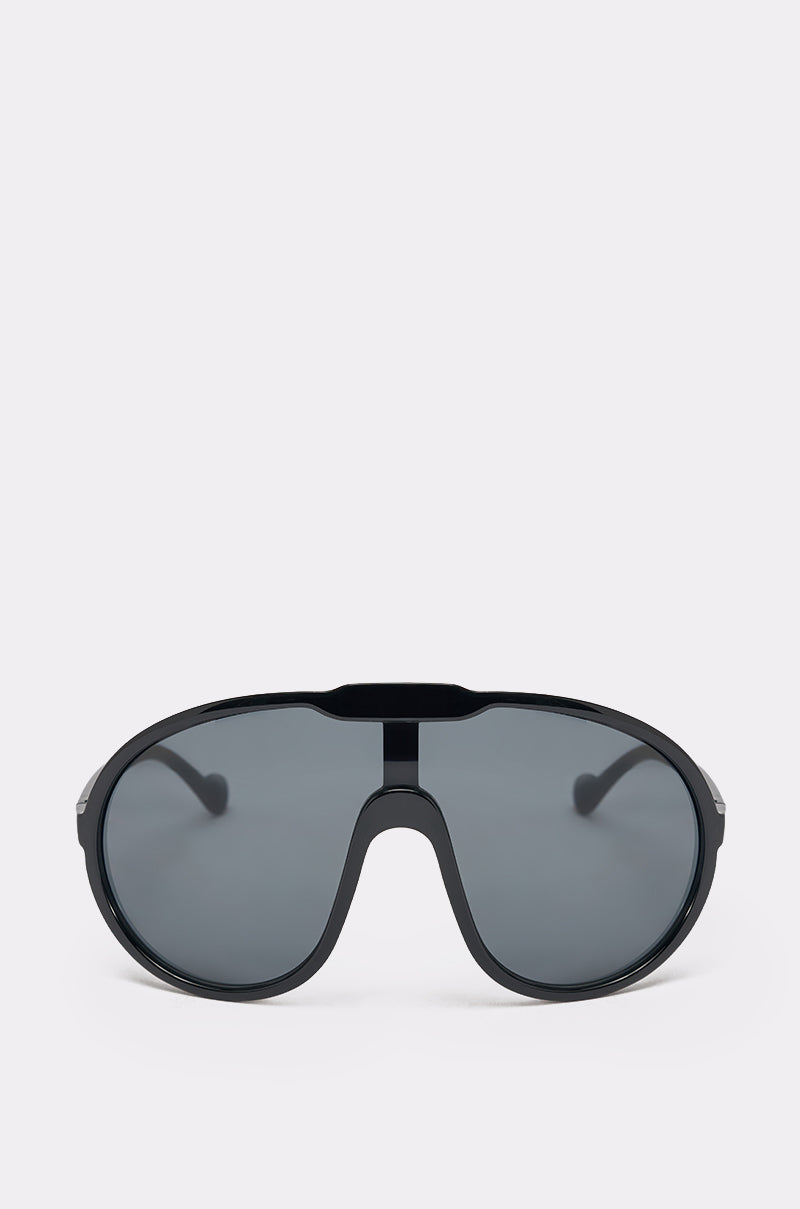The BIGGER IS BETTER BLACK SUNGLASSES feature a single, continuous dark tinted lens and a thick black frame in a sporty shield style, shown against a plain light grey background. 1