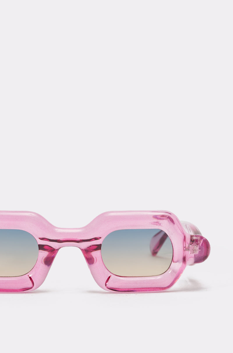 Close-up of JELLY SUNGLASSES featuring chunky, translucent pink frames and blue-gradient lenses in a bold rectangular design, set against a plain white background. 3