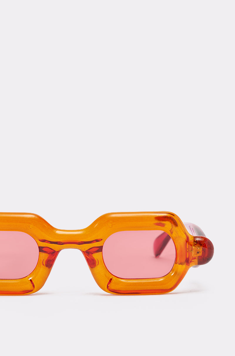 Close-up of the SORBET SUNGLASSES, featuring chunky orange rectangular frames and rosy tinted lenses, photographed against a plain white background. Only the top half of the sunglasses is visible. 4