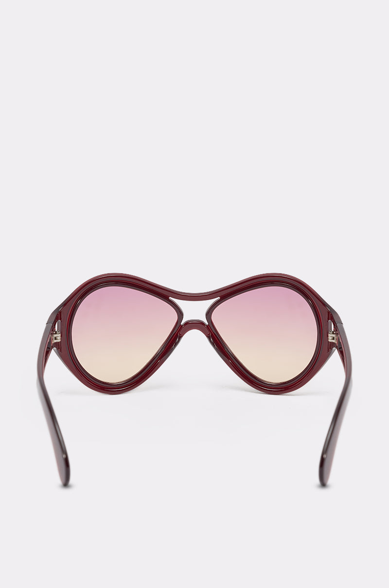 The WILLY SUNGLASSES feature a retro-inspired maroon double-bridge frame and gradient pink-tinted lenses, shown from the front against a plain light background. 3