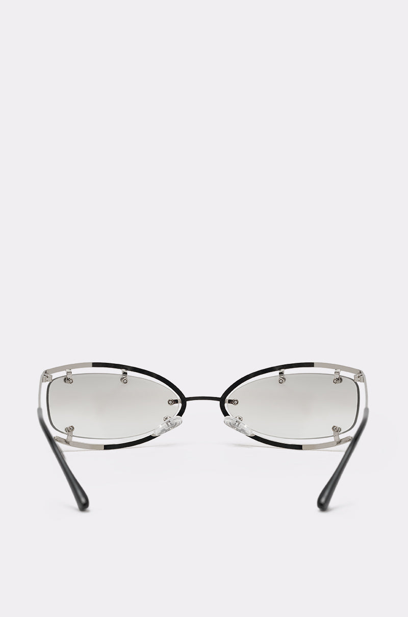 The U SEE ME GLASSES feature a minimalist oval design with a thin silver-tone metal frame and lightly tinted lenses, shown on a plain white background. The glasses are facing forward, arms slightly outward. 5