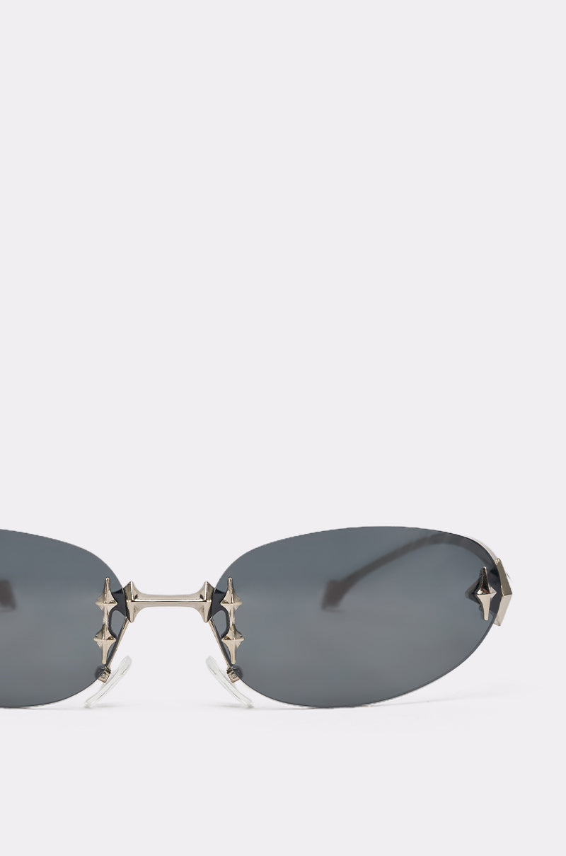 Close-up of CYBER SUNGLASSES with dark oval lenses and bold metallic star-shaped details at the bridge and edges, set against a plain light background. 5
