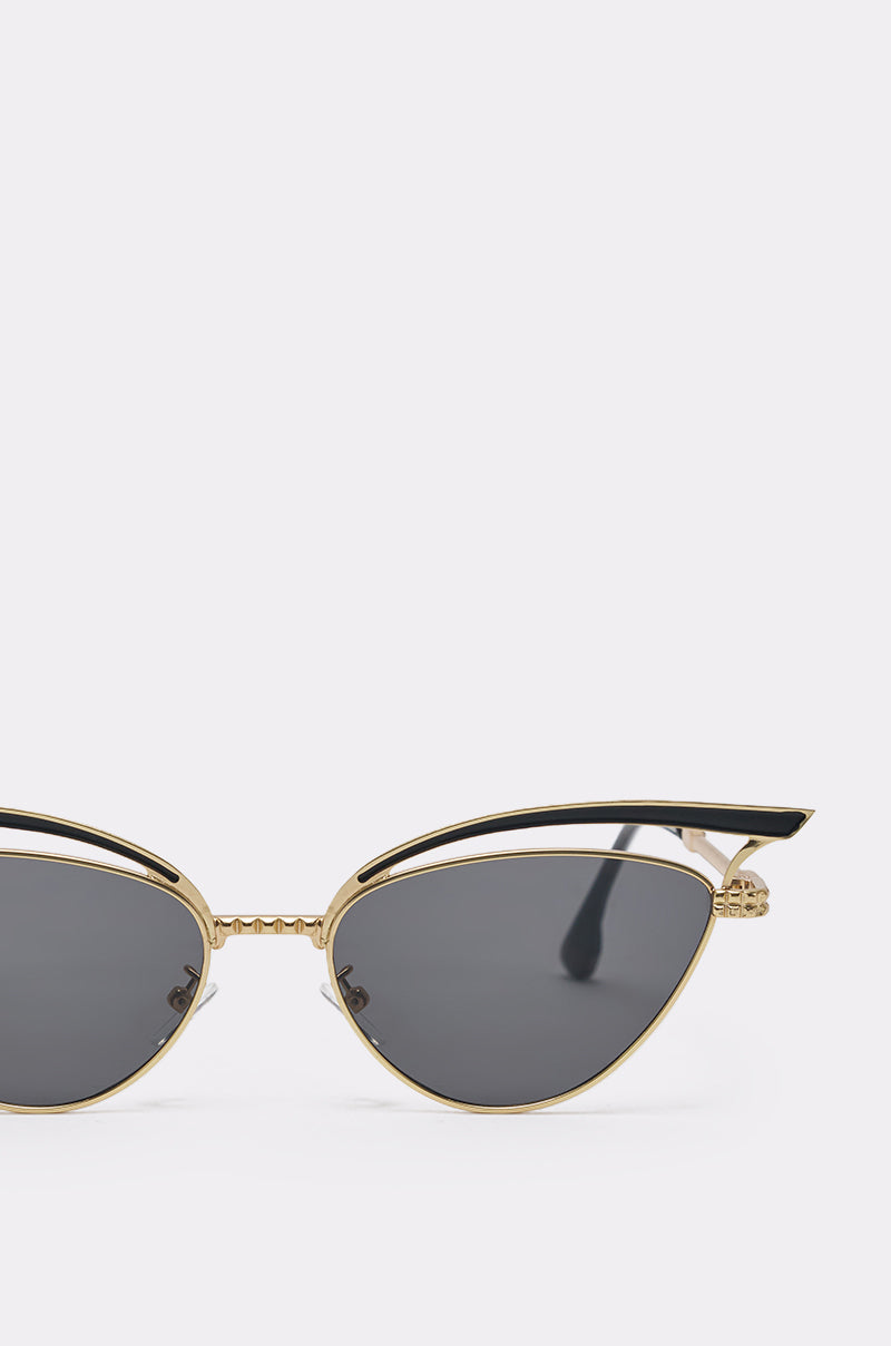 Close-up of AUDREY SUNGLASSES featuring chic cat-eye style, gold-accented frame, black upper rims, and dark tinted lenses. The upper half of these fashionable sunglasses is displayed against a plain light background. 4